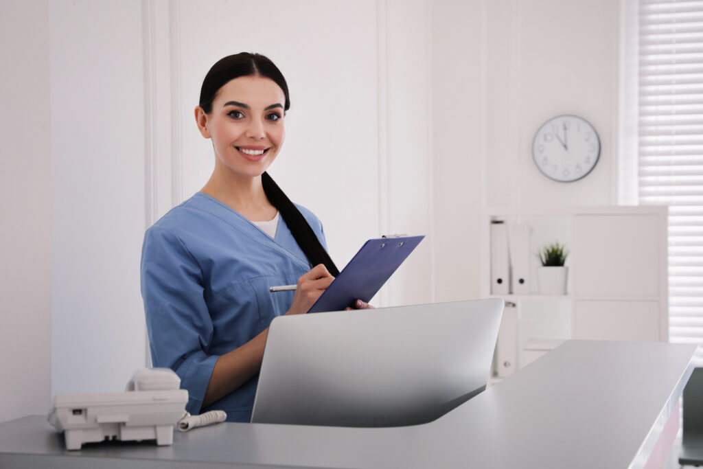 Healthcare professional in blue scrubs smiling while holding a clipboard, representing healthcare jobs in the UK.